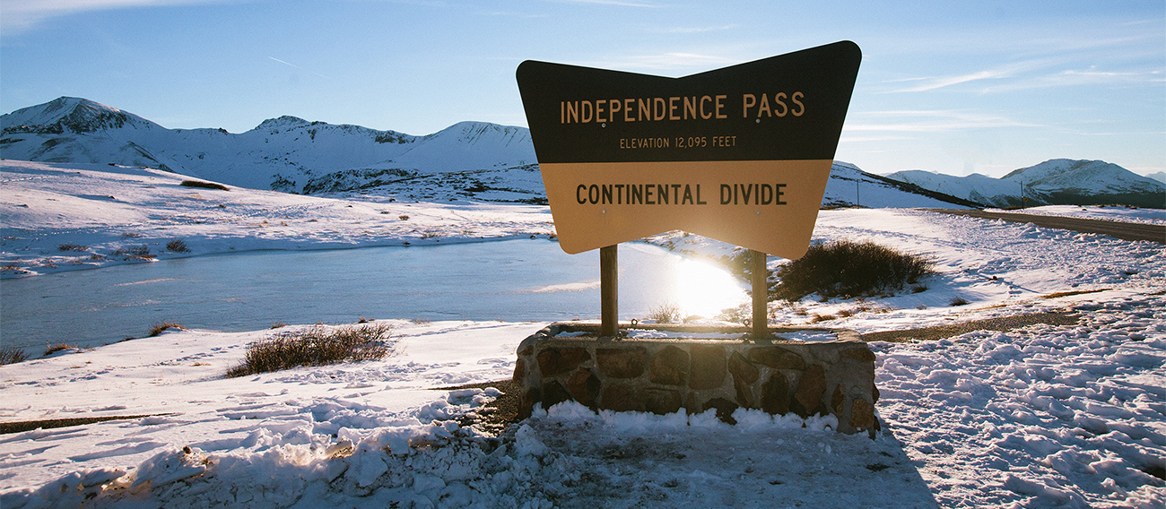 Independence Pass summit sign in winter with snow around
