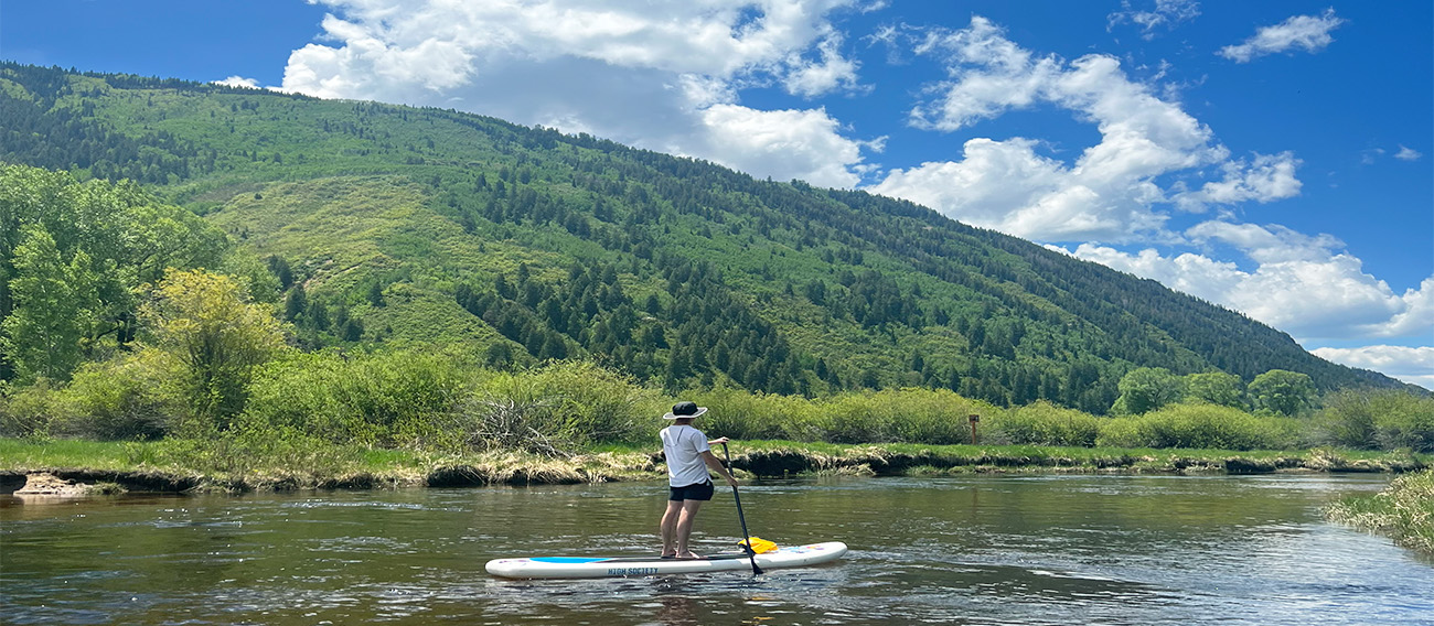 Man on Stand Up Paddleboard going down Still Water In Aspen, Colorado
