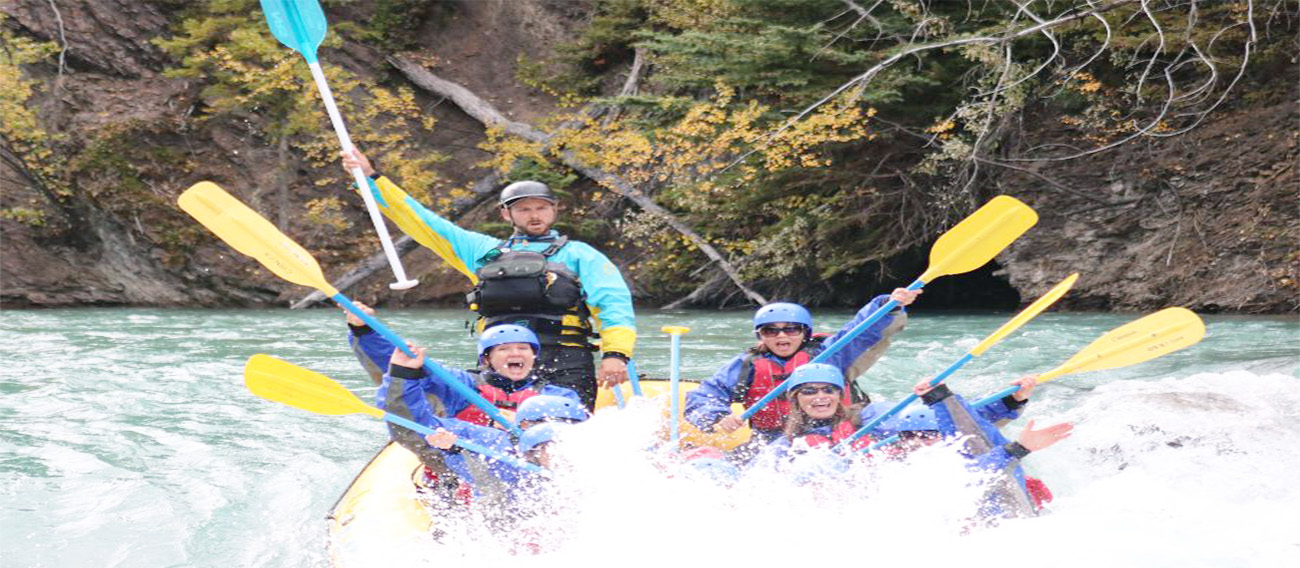 Seven people on White Water Raft going down rapids with guide  