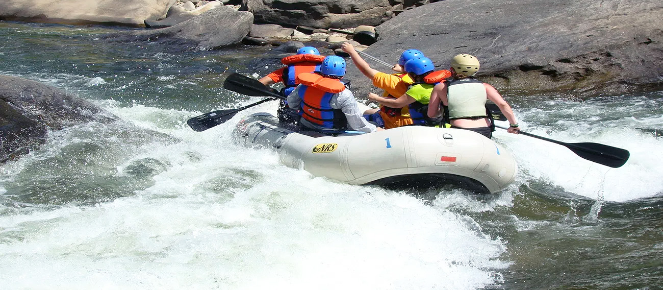 Group of five people going down rapids on White Water Raft